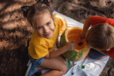 Cute girl and boy carving a pumpkin