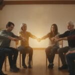 Close-up of intertwined hands forming a circle in a church setting, symbolizing Christian unity